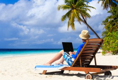 adam ile tatil tropikal üstünde laptop