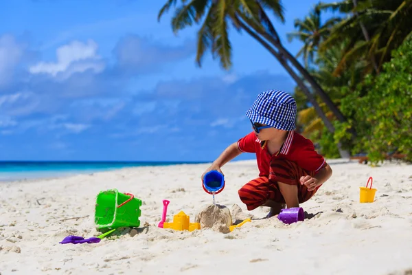 Mały chłopiec bawiący się piaskiem na plaży — Zdjęcie stockowe