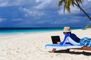 adam ile tatil tropikal üstünde laptop