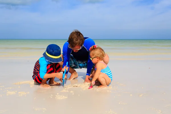 Father and  kids playing with sand on summer beach — Stock Photo, Image