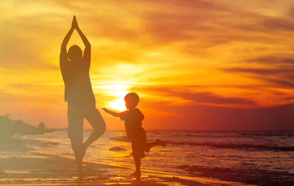 Vader en zoon doen yoga bij zonsondergang zee — Stockfoto