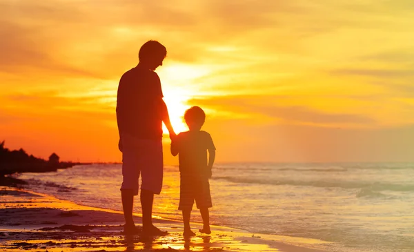 Vader en zoon hand in hand op zonsondergang zee — Stockfoto