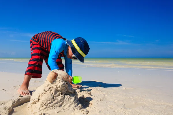 Niño pequeño cavando arena en la playa tropical — Foto de Stock