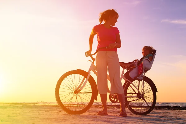 Мать и ребенок катаются на велосипеде на закате — стоковое фото