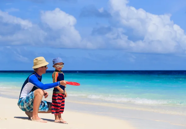 Padre e hijo jugando con disco volador en la playa — Foto de Stock