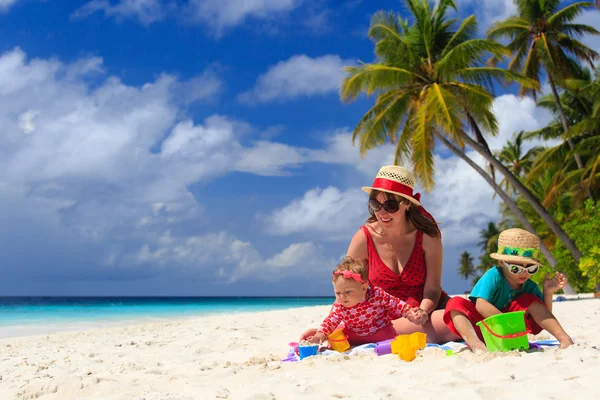 Mutter und Kinder spielen am tropischen Strand — Stockfoto