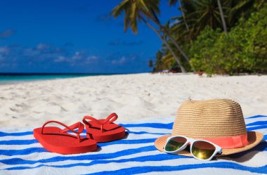 şapka, güneş gözlüğü ve tropikal bir plajda flip flop