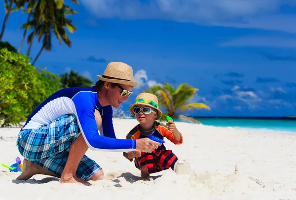 Vader en zoon spelen met water geweren op het strand — Stockfoto