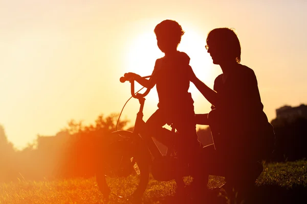 Pai e filho se divertindo andando de bicicleta ao pôr do sol — Fotografia de Stock