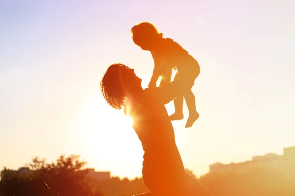 Silhouettes of father and little daughter playing at sunset — Stock Photo, Image