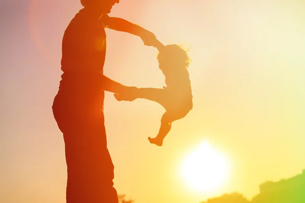 Siluety otce a malá dcera hraje při západu slunce — Stock fotografie