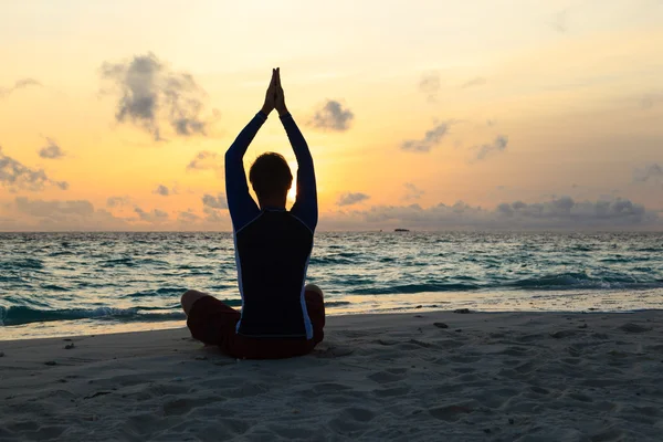 Gün batımında yoga yaparken genç adam silüeti — Stok fotoğraf