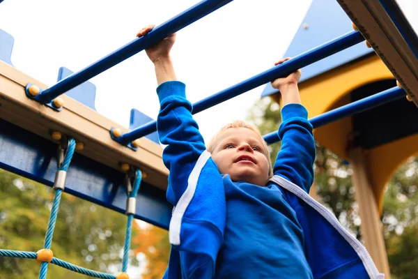 Menino brincando em barras de macaco no outono — Fotografia de Stock