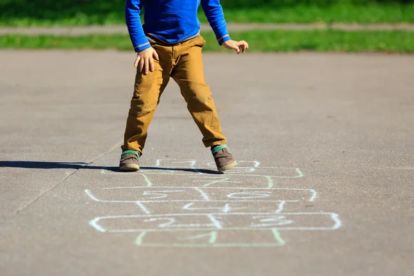 Pequeno menino jogar hopscotch no playground — Fotografia de Stock