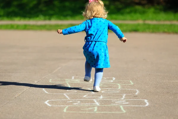 Маленькая девочка играет в классики на детской площадке — стоковое фото