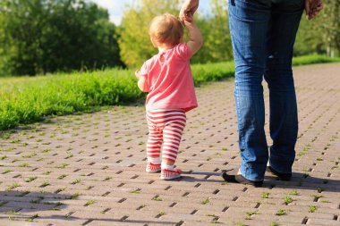 little girl making first steps in the park clipart