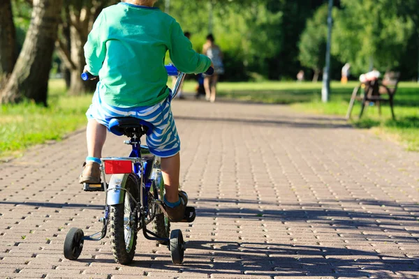 Маленький мальчик катается на велосипеде в летнем парке — стоковое фото