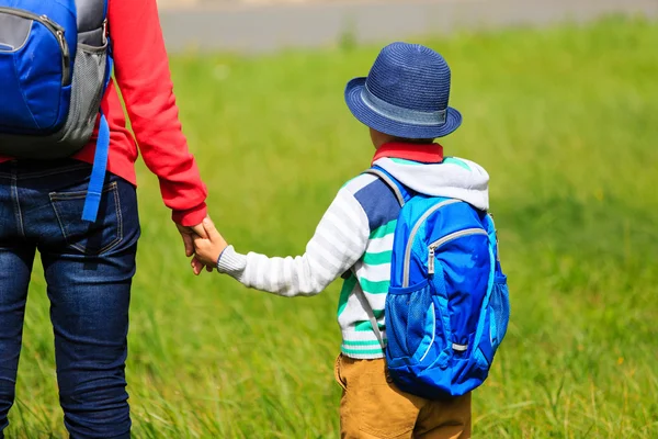 Мать держит за руку маленького сына с рюкзаком на улице — стоковое фото
