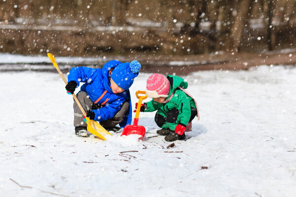 little boy and girl digging snow in winter