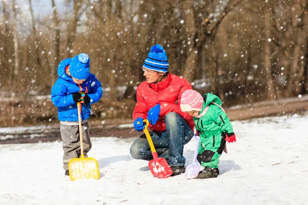 Батько і діти копають сніг в зимовому парку — стокове фото