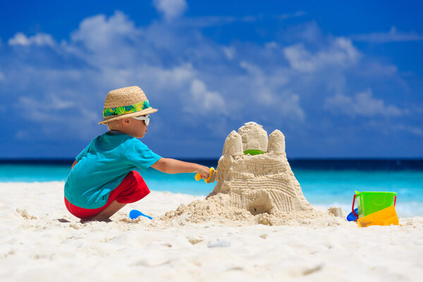 child building sand castle on tropical beach