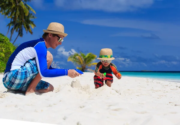 Father and son playing with water guns on the beach — Stock Photo, Image