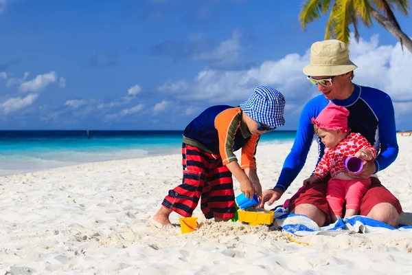 Padre e figli che fanno il castello di sabbia sulla spiaggia tropicale — Foto Stock