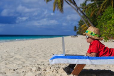 little boy with laptop at the beach