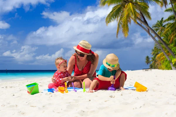 Moeder en kinderen spelen op tropisch strand — Stockfoto