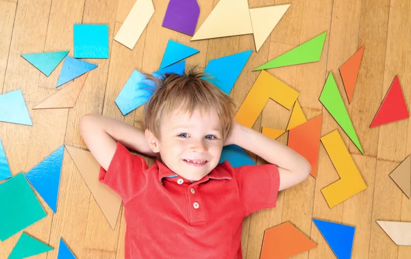 Happy little boy with puzzle toys on wooden floor — Stock Photo, Image