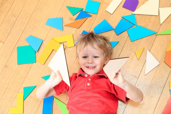 Happy little boy with puzzle toys on wooden floor — Stock Photo, Image