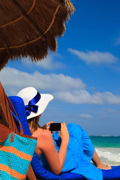 Женщина с мобильным телефоном на тропическом пляже — стоковое фото