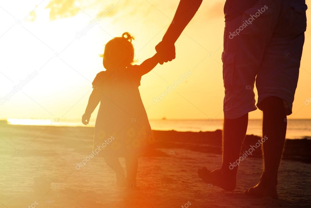 father and little daughter walking on the beach