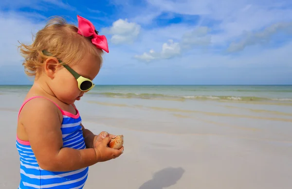 Carino bambina giocare con conchiglie sulla spiaggia — Foto Stock