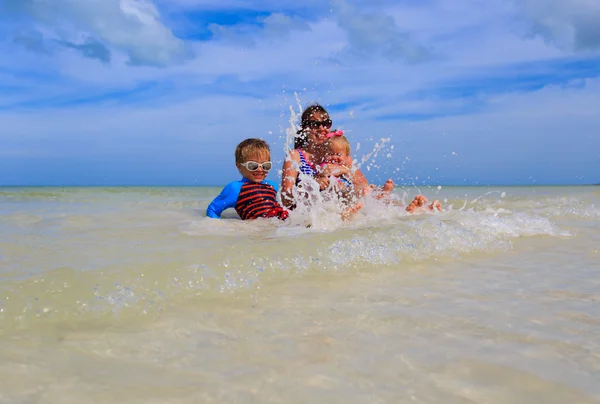 Mère avec deux enfants éclaboussant l'eau à la mer — Photo