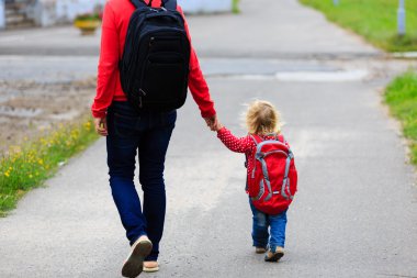 Sırt çantası ile küçük kızının elini tutarak anne