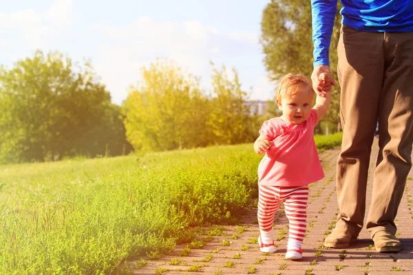 Erste Schritte eines kleinen Mädchens mit Papa im Park — Stockfoto