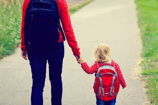 Мать держит за руку маленькую дочь с рюкзаком — стоковое фото