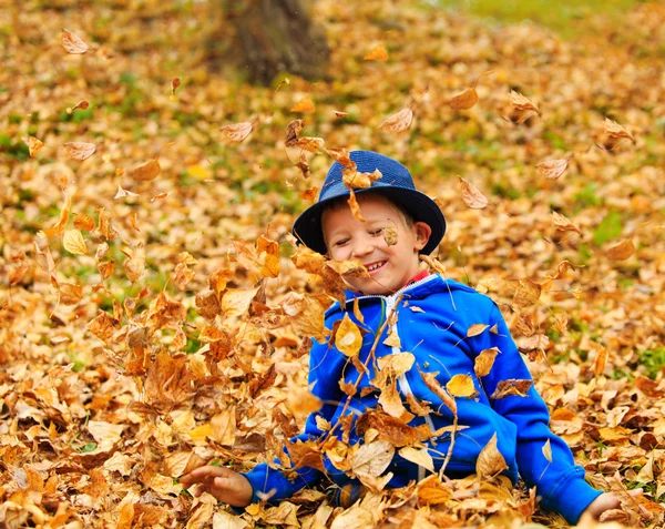 Cute anak kecil bermain dengan daun di musim gugur — Stok Foto