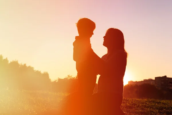 Mãe feliz e filho pequeno ao pôr do sol — Fotografia de Stock