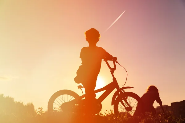 Маленький хлопчик їде на велосипеді на заході сонця — стокове фото