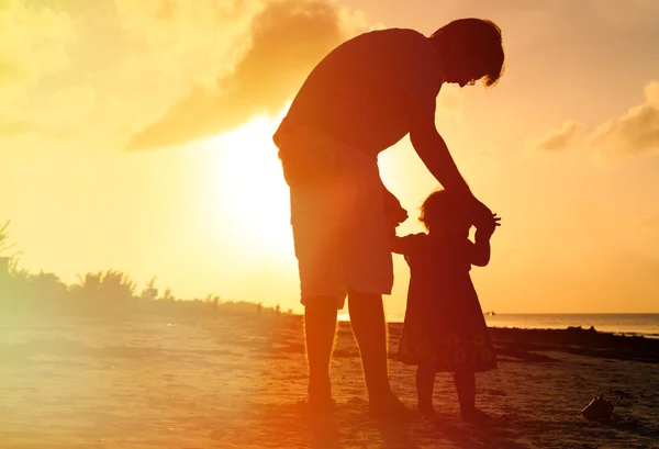 Père et petite fille marchant sur la plage au coucher du soleil — Photo