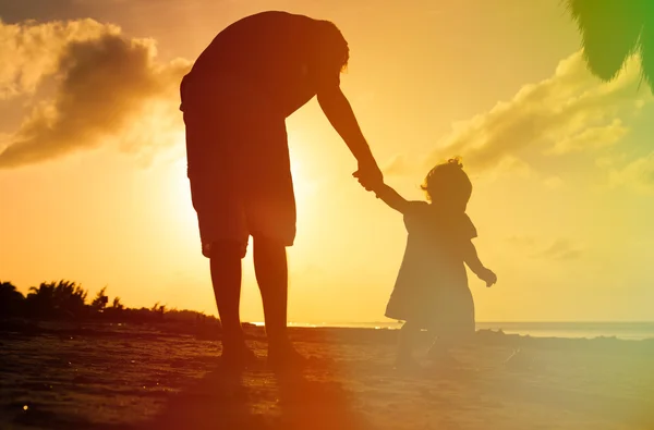 Otec a malá dcera procházky na pláži při západu slunce — Stock fotografie