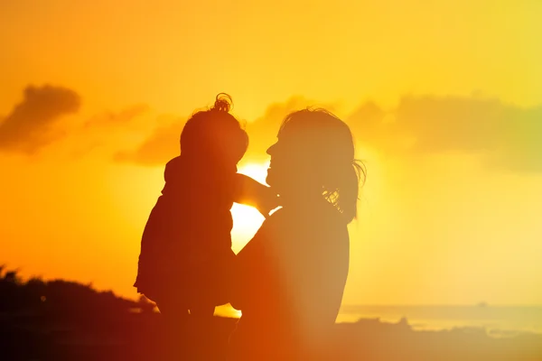 Мати і маленька дочка грають на заході сонця — стокове фото