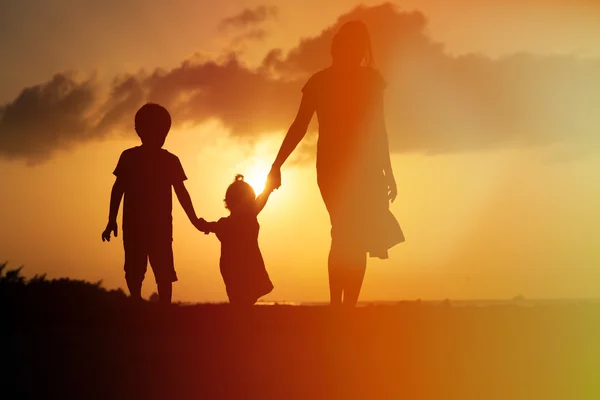 Mother and two kids walking at sunset — Stock Photo, Image