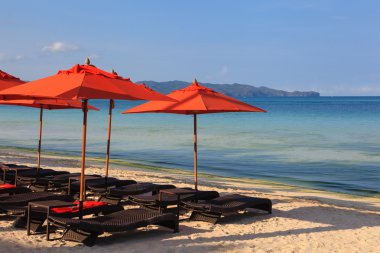 Plaj sandalyeleri ve tropikal kum plaj avucunda