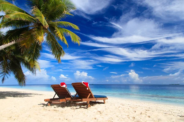 Due sedie a sdraio con cappelli rossi di Babbo Natale sulla spiaggia — Foto Stock