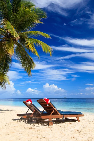 Dos salones de sillas con sombreros rojos de Santa en la playa —  Fotos de Stock