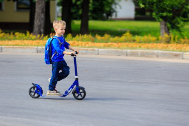 Küçük çocuk şehirde scooter kullanıyor.