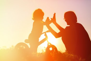 Baba ve kızı gün batımında bisiklet sürerken eğleniyorlar.